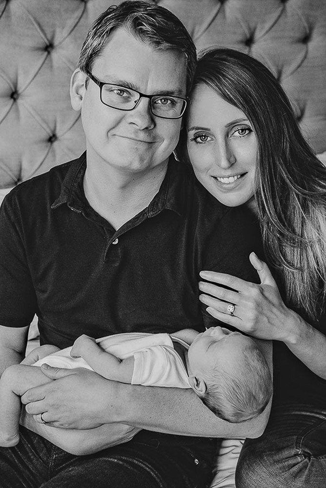 family portrait with a newborn baby sleeping in his father's arms during newborn photoshoot at home london